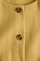 Chaleco mostaza con cuello redondo, cierre frontal con botones y diseño forrado.