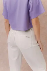 Jeans de tiro alto y silueta barrel, color crudo, con cinco bolsillos, presillas para cinturón y cierre frontal con botón y cremallera. Presenta diseño de pierna amplia con leve entalle hacia el ruedo y dobladillo vuelto.