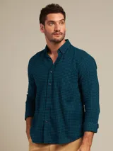 Camisa de manga larga a cuadros pequeños en tonos celeste y azul marino, con cuello abotonado y bolsillo en el pecho.
