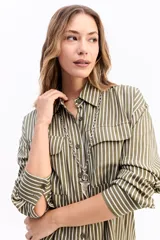 Camisa de manga larga con estampado de rayas verticales en tonos azul y blanco. Presenta cuello clásico, cierre frontal con botones y dos bolsillos tipo cargo en el pecho. Su diseño es de corte relajado y holgado.