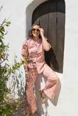 Camisa de lino con estampado floral en tonos rosados y naranjas, de corte recto, cuello mao y cierre frontal con botones. Presenta mangas al codo con frunces en los hombros.