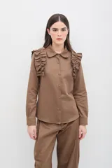 Camisa de gabardina de tencel color negro, con cuello clásico, cierre frontal de botones y volados fruncidos en los hombros.