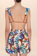 Short de playa con estampado botánico en tonos blanco, azul, verde y marrón. Presenta cintura elástica fruncida y corte estructurado con pliegues frontales.