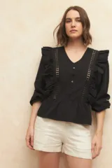 Blusa color verde claro con textura arrugada, escote en V, cierre frontal con botones, mangas 3/4 con puños elásticos y detalles de encaje y volados en el frente y los hombros.