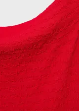 Vestido midi entallado de color rojo, con cuello barco y hombros descubiertos. Presenta un tejido con textura y abertura posterior en el bajo.
