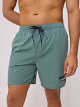 Short de baño tipo volley color verde azulado, con cintura elástica y cordón de ajuste en color azul marino. Presenta un parche con el logo de la marca en la pierna izquierda y aberturas laterales en el ruedo.