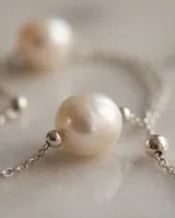 Collar de tres niveles elaborado en plata 925, con una perla de río central en cada cadena y pequeños detalles esféricos en la estructura.