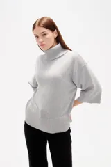 Polera de tejido de punto color gris, con cuello alto, mangas 3/4 y diseño holgado.
