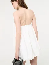 Vestido corto negro, estilo globo o balloon, con escote corazón pronunciado. Se lleva sobre una remera blanca de manga corta.