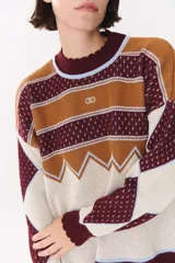 Buzo de tejido de punto con diseño geométrico y combinación de colores en contraste. Presenta cuello redondo, mangas largas y corte oversized.