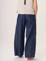 Pantalón ancho de denim azul oscuro, con corte holgado y costuras contrastantes en blanco y rojo en la zona de la bragueta.