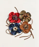 Broche en forma de flor realizado en cuero, con diseño artesanal de pétalos superpuestos.