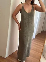 Vestido largo tejido en hilo de algodón y lurex color beige claro, con escote en V, tiras regulables en los hombros y tajos laterales. Presenta un patrón de puntos calados en forma de zigzag.