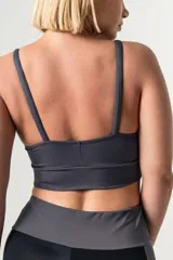 Top deportivo de color azul francia, con escote redondo, breteles finos ajustables y detalle de aros metálicos en la unión de los breteles con el frente. Presenta una faja ancha de doble tela en la base para mayor soporte.