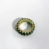 Anillo dorado con cristales verdes engarzados en toda su extensión.