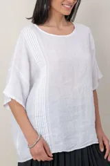 Blusa de lino color marrón oscuro, con escote redondo, mangas cortas amplias y detalle de alforzas verticales en el lateral derecho.