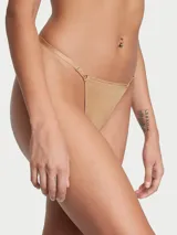 Panty tipo tanga en tono praline, confeccionado con microfibra suave de tiro bajo, con tirantes ajustables y herrajes dorados.