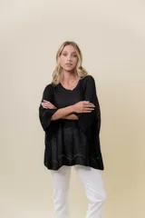 Buzo de tejido liviano con brillo sutil tipo lurex, color beige o dorado claro. Presenta un calce suelto (oversize) con mangas amplias y cuello redondo. El ruedo tiene un detalle de terminación festoneado con pequeños calados.