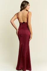 Vestido largo de satén color bordó, con escote profundo en V, tirantes finos y espalda descubierta. Presenta un corte ajustado en el torso que se ensancha suavemente hacia el ruedo.