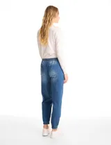 Pantalón tipo jogger de denim azul con efecto lavado. Presenta cintura elástica con cordón ajustable, bolsillos laterales y traseros, y puños elásticos en los tobillos.