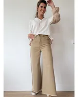 Pantalón de jean color beige, de corte recto y tiro alto, con ruedo deshilachado y cierre frontal con botón y cremallera.