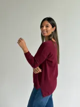 Sweater de punto en color bordó, con escote en V, mangas largas y diseño de corte recto con dobladillo ligeramente más largo en la parte posterior.