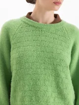 Sweater de tejido de punto color verde, con cuello redondo, mangas largas con hombros caídos y puños acanalados. Presenta un diseño de textura sutil en el frente.