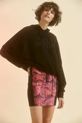 Minifalda de tiro alto con cierre frontal y elástico en la cintura. Presenta recortes laterales en color negro y estampado paisley en tonos rosa y violeta.