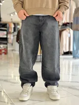 Pantalón de jean estilo baggy, color gris oscuro con efecto acid wash, corte oversize y diseño holgado.