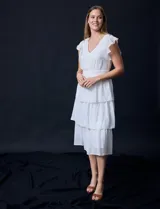 Vestido blanco de gasa con capas, marca Julia Jordan. Escote en V, manga corta con volados, corte en cintura y abertura central en espalda con cierre invisible.