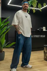 Pantalón de jean azul oscuro de corte wide leg, con diseño holgado y tiro medio. Presenta un pequeño bordado con alas en el bolsillo delantero.