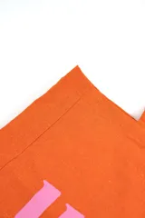 Bolso tote naranja de lona con estampado gráfico amarillo que forma la palabra "FRESH" simulando un gajo de cítrico, y la inscripción "INDIAN" en la parte inferior. Cuenta con dos asas superiores para llevar al hombro.