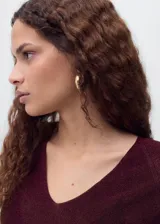 Jersey de punto fino con acabado brillante de lúrex, cuello en pico y manga larga. Presenta un diseño recto y entallado.
