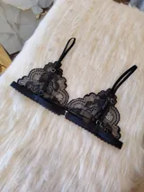 Bralette negro de encaje con diseño triangular, breteles regulables y cierre trasero con gancho.