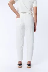Pantalón jean de corte carrot color crudo, tiro alto, con bolsillos laterales y traseros, y cierre frontal con botón y cremallera.