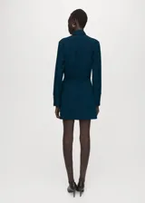 Vestido corto azul oscuro, de manga larga y escote en V, con detalle de bufanda integrada al cuello y fruncidos laterales en la falda.