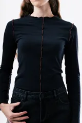 Camiseta de manga larga en color gris oscuro, con cuello redondo y costuras decorativas expuestas en el frente. Presenta un diseño ajustado al cuerpo.