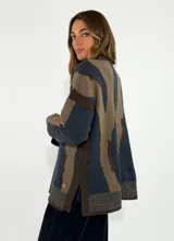 Sweater de tejido de punto con diseño abstracto de rayas irregulares en tonos azul y marrón. Presenta cuello redondo, mangas largas con caída de hombro y puños y ruedo acanalados.