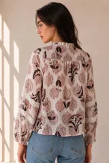 Camisa de manga larga con estampado floral en tonos azules y blancos, cuello con volados y detalles de encaje a lo largo de la botonadura y en las mangas.
