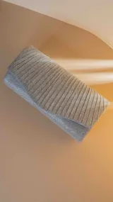 Sobre de fiesta rígido color plateado con textura acanalada y cierre de broche imantado.