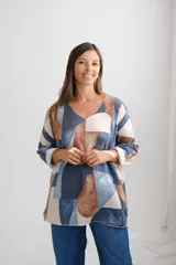 Sweter de punto amplio con escote en V y manga larga, presenta un diseño estampado con bloques geométricos en tonos azul, marrón y beige.