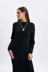 Vestido midi de punto en color negro, con cuello alto y mangas largas con puños ajustados. Presenta un diseño minimalista y entallado.