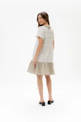 Vestido corto de algodón a rayas horizontales color beige, con cuello redondo negro y falda negra de lino.