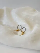 Par de aros plateados tipo argolla con dije circular de nácar.