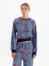 Camisa de viscosa con diseño estampado de corazones rojos sobre fondo azul con manchas. Presenta cuello redondo, puños y ruedo tejidos en ribb, con mangas largas abullonadas y hombros caídos.