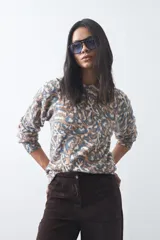 Sweater de punto con diseño de estampado animal print abstracto en tonos tierra y azul claro. Presenta cuello redondo a la base, mangas largas levemente amplias y terminaciones acanaladas en puños y ruedo.