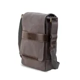 Morral de tela canvas gris con detalles en cuero sintético marrón. Cuenta con solapa frontal con cierre magnético, bolsillo tipo guantera bajo la solapa, división interna desmontable con velcro y correa larga regulable.