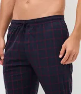Pantalón de pijama tipo jogger para hombre, confeccionado en tejido plush suave y abrigado. Presenta un diseño estampado a cuadros, cintura elástica con cordón de ajuste y puños elásticos en los tobillos.