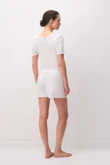 Short de pijama blanco de 100% algodón, con diseño texturado a rayas verticales, cintura elástica con botones decorativos y detalles de ondas en el ruedo.