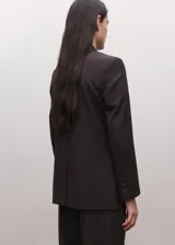 Blazer cruzado de doble botonadura, color marrón oscuro, con solapas de muesca, bolsillos con solapa y hombreras estructuradas.